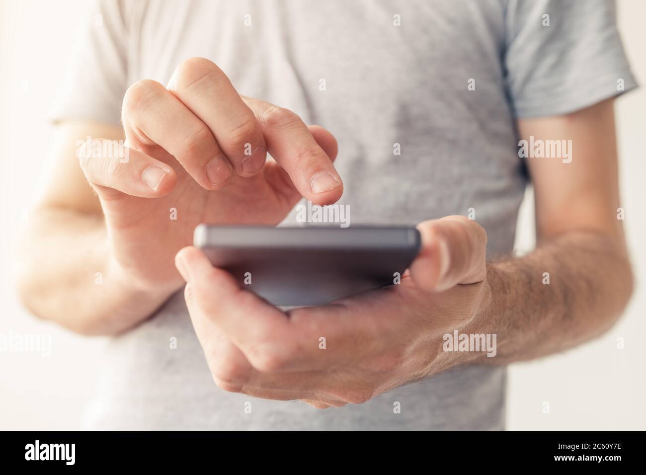 Primo piano di mani maschili che digitano messaggi di testo sullo smartphone, messa a fuoco selettiva Foto Stock