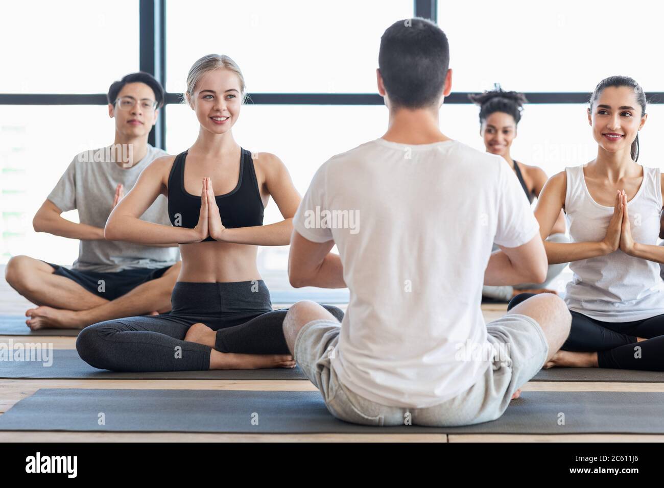 Yoga con istruttore. Gruppo di giovani che praticano esercizi di meditazione con Trainer Foto Stock