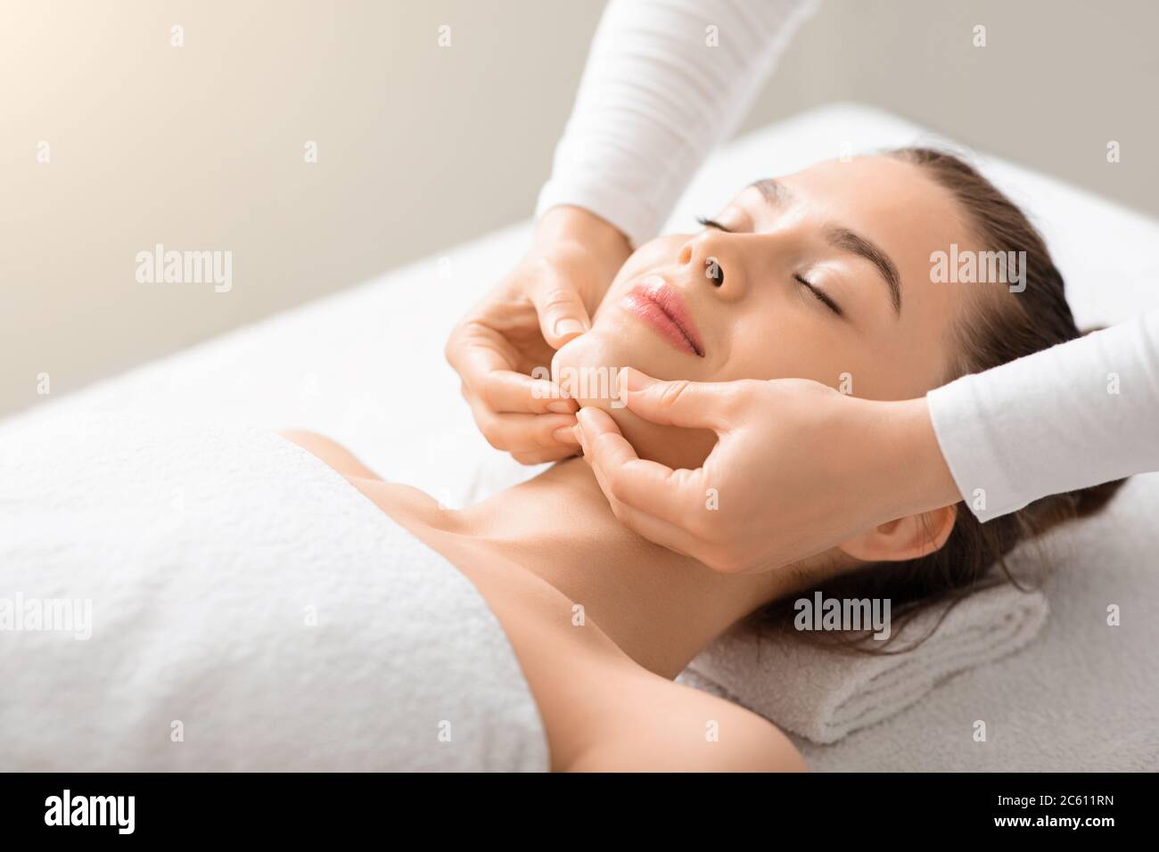 Giovane donna rilassata con massaggio viso sollevabile presso il centro benessere Foto Stock