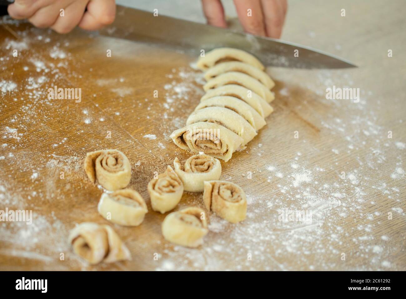 Primo piano femmina fette di panettiere rotolo di pasta fa panini con zucchero cannella per panini Foto Stock