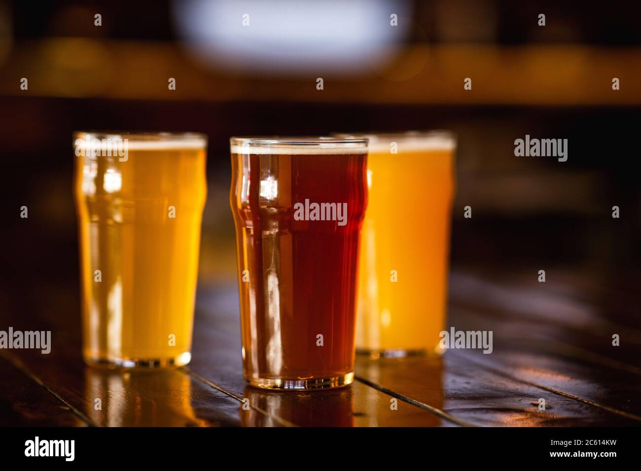 Orzo, non filtrato, birra leggera in bicchieri su tavola di legno in interni poco nitidi Foto Stock