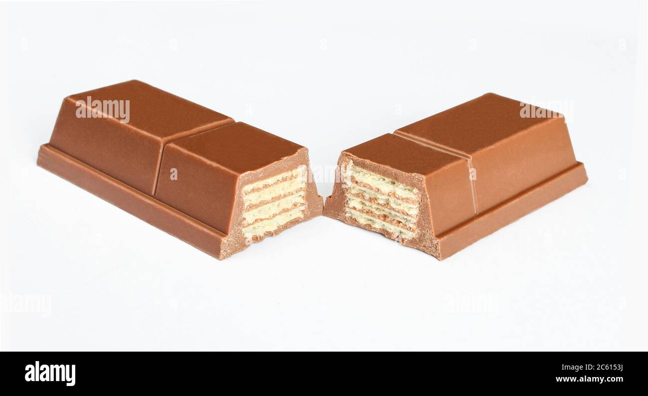 Dolci al wafer ricoperti di cioccolato. Due pezzi di barra di cioccolato riempiti di strati croccanti isolati su sfondo bianco Foto Stock