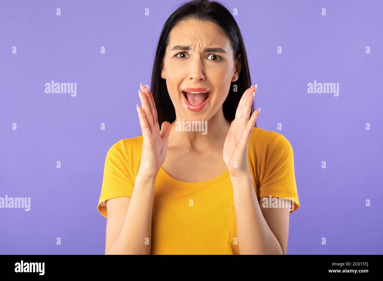 Giovane donna grimacing, urlando allo studio viola Foto Stock