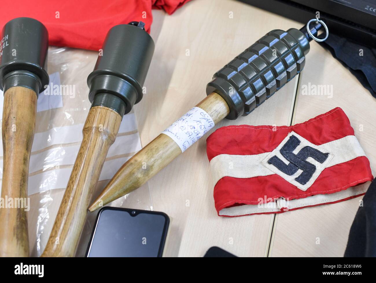 Eberswalde, Germania. 06 luglio 2020. Granate e materiali a mano, tra cui un bracciale con una swastika, sono stesi su un tavolo in occasione di un evento stampa presso l'LKA Brandenburg dopo un raid contro il gruppo neo-nazista 'Freie Kräfte Prignitz'. Credit: Jens Kalaene/dpa-Zentralbild/dpa/Alamy Live News Foto Stock
