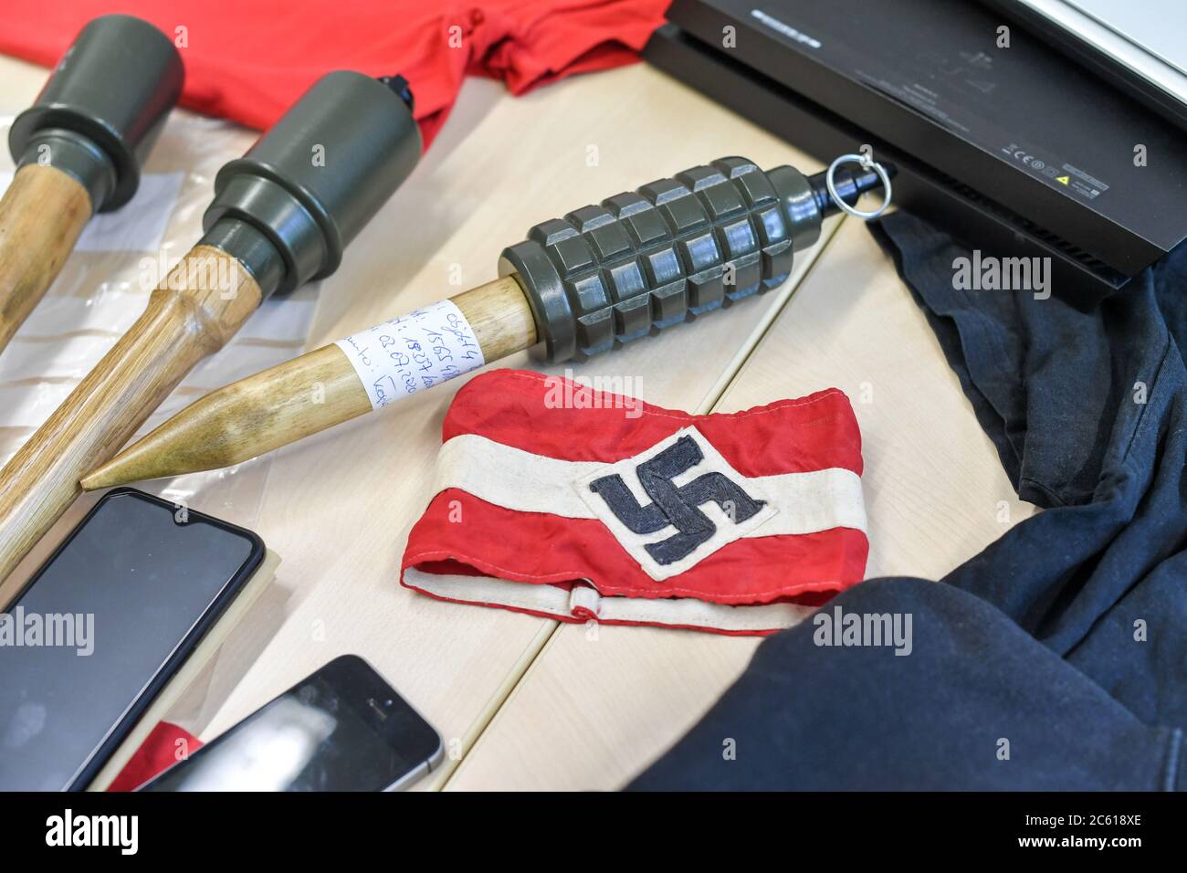 Eberswalde, Germania. 06 luglio 2020. Granate e materiali a mano, tra cui un bracciale con una swastika, sono stesi su un tavolo in occasione di un evento stampa presso l'LKA Brandenburg dopo un raid contro il gruppo neo-nazista 'Freie Kräfte Prignitz'. Credit: Jens Kalaene/dpa-Zentralbild/dpa/Alamy Live News Foto Stock