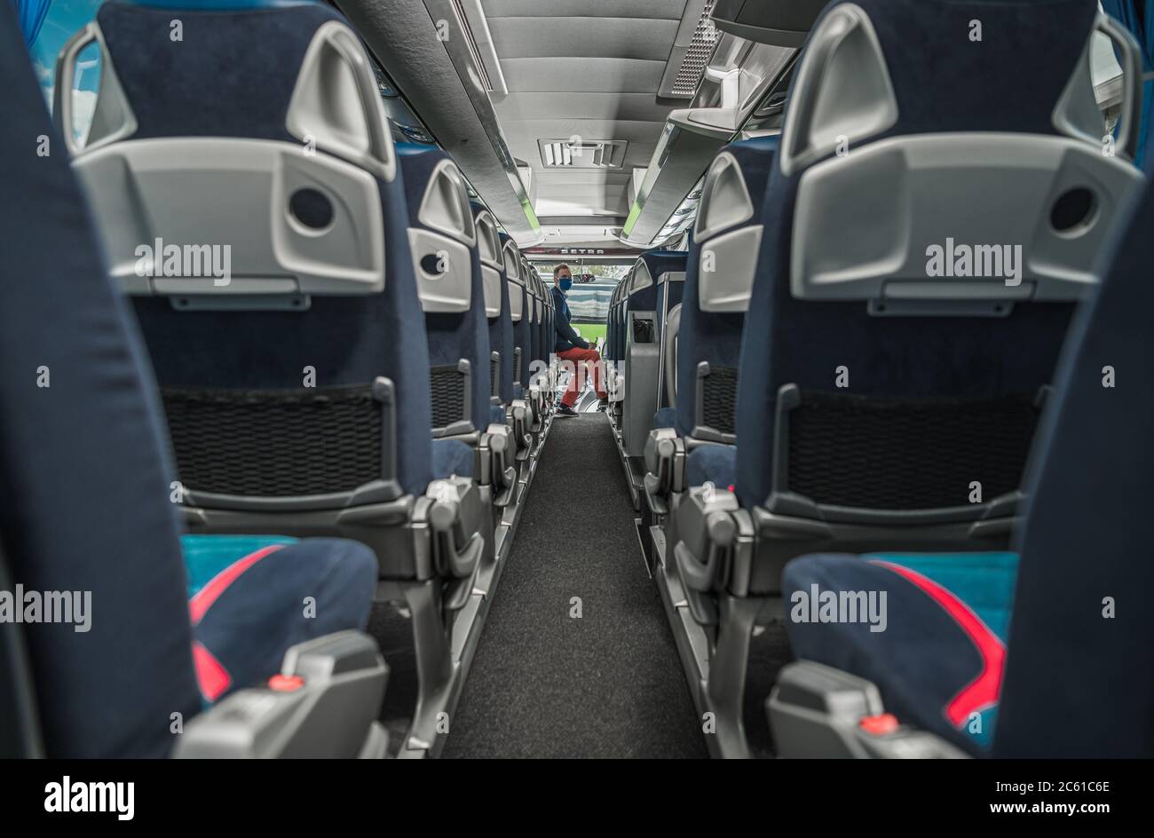 Autista caucasico di bus navetta nei suoi 40 passeggeri in attesa all'interno del veicolo durante epidemia di virus Pandemic. Tema problemi del settore dei trasporti. Foto Stock