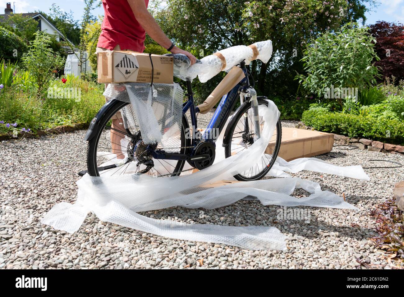 Consegna a domicilio di bicicletta elettrica ebike ordinata online durante il coronavirus lockdown - bici tolta fuori dal box e confezione di bolle di sconfezionamento - UK Foto Stock