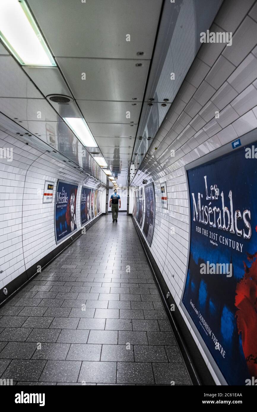 Una donna che cammina lungo un passaggio vuoto in una stazione sulla Central Line del sistema metropolitano di Londra Foto Stock