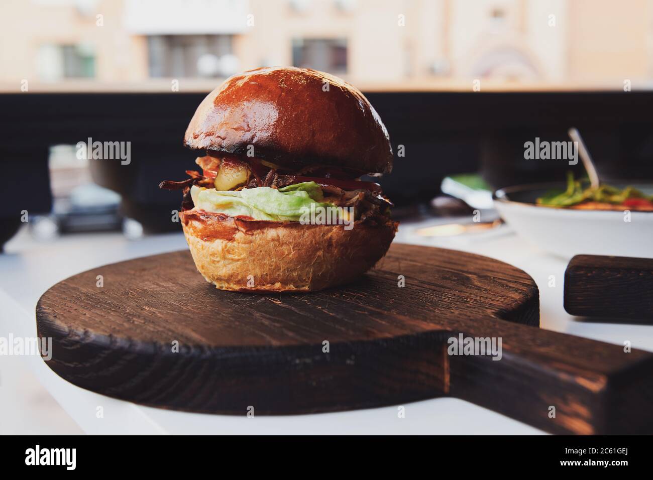 Hamburger con carne d'anatra sul bordo di legno al ristorante. Panino fresco con lattuga e cetriolo sottaceto. Foto Stock