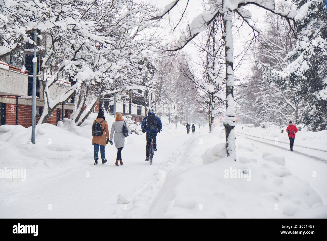 Strade della città dopo la tempesta di neve invernale Blizzard. Le gite in bicicletta e i pedoni camminano in inverno sulla strada innevata Foto Stock