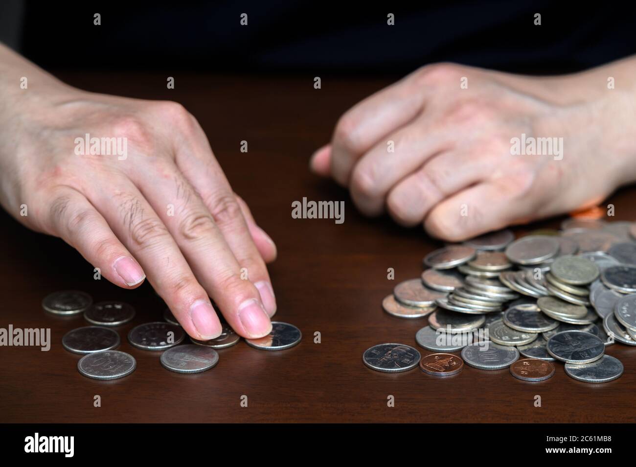 le mani di un uomo che smista monete impilate. Foto Stock