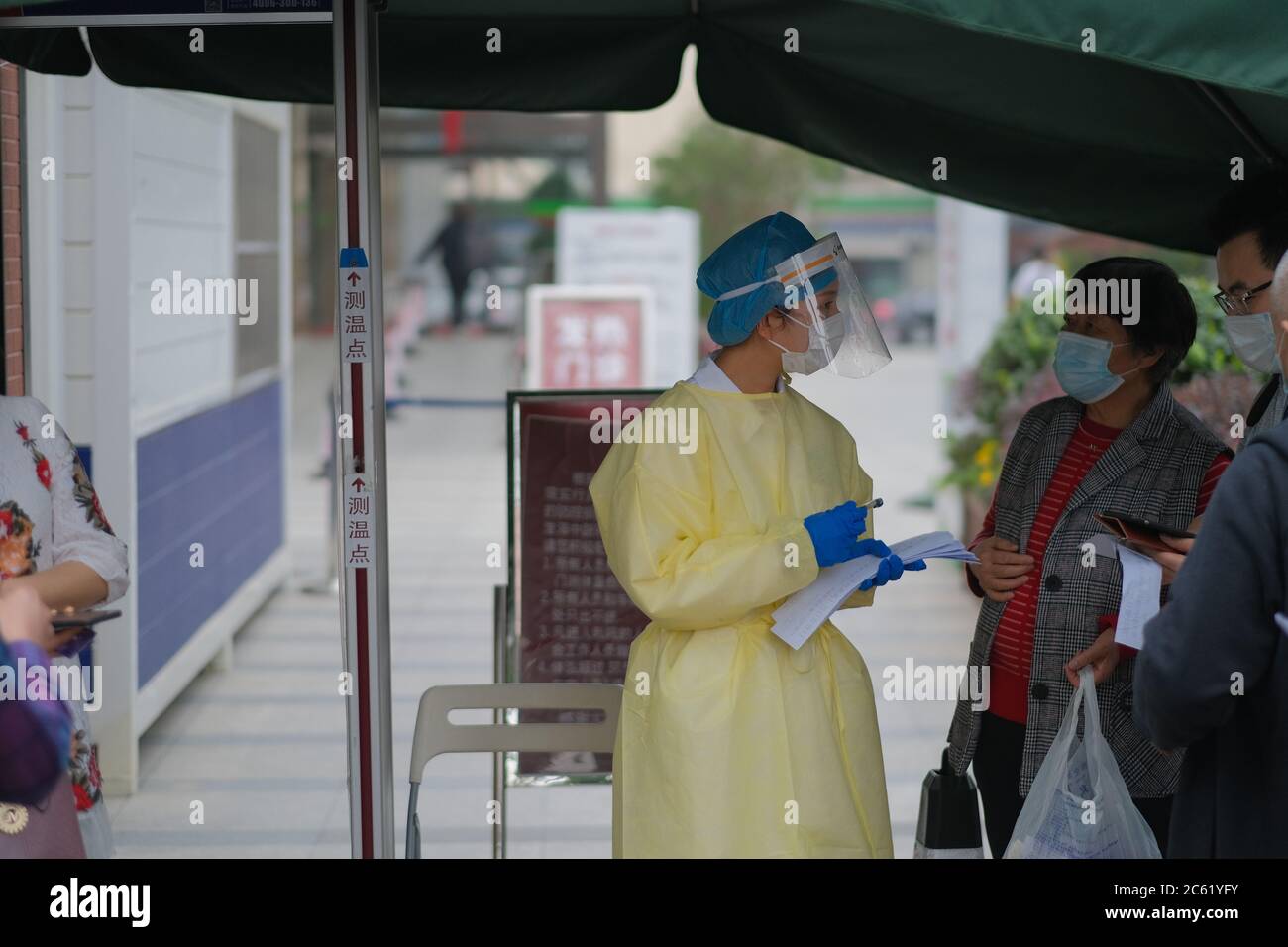Medico che parla con i visitatori all'ingresso dell'ospedale, indossando maschera facciale e indumenti protettivi per evitare il coronavirus. Foto Stock