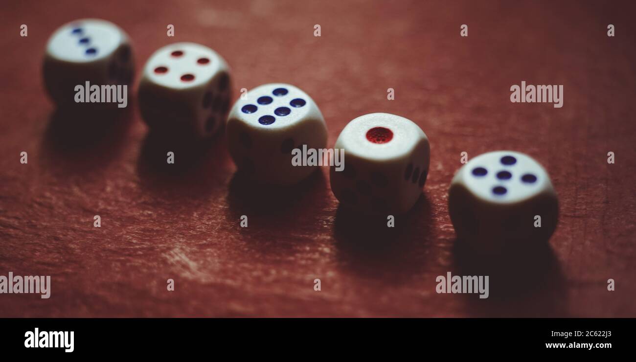 Set di dadi di gioco su tavolo rosso scuro. Foto Stock