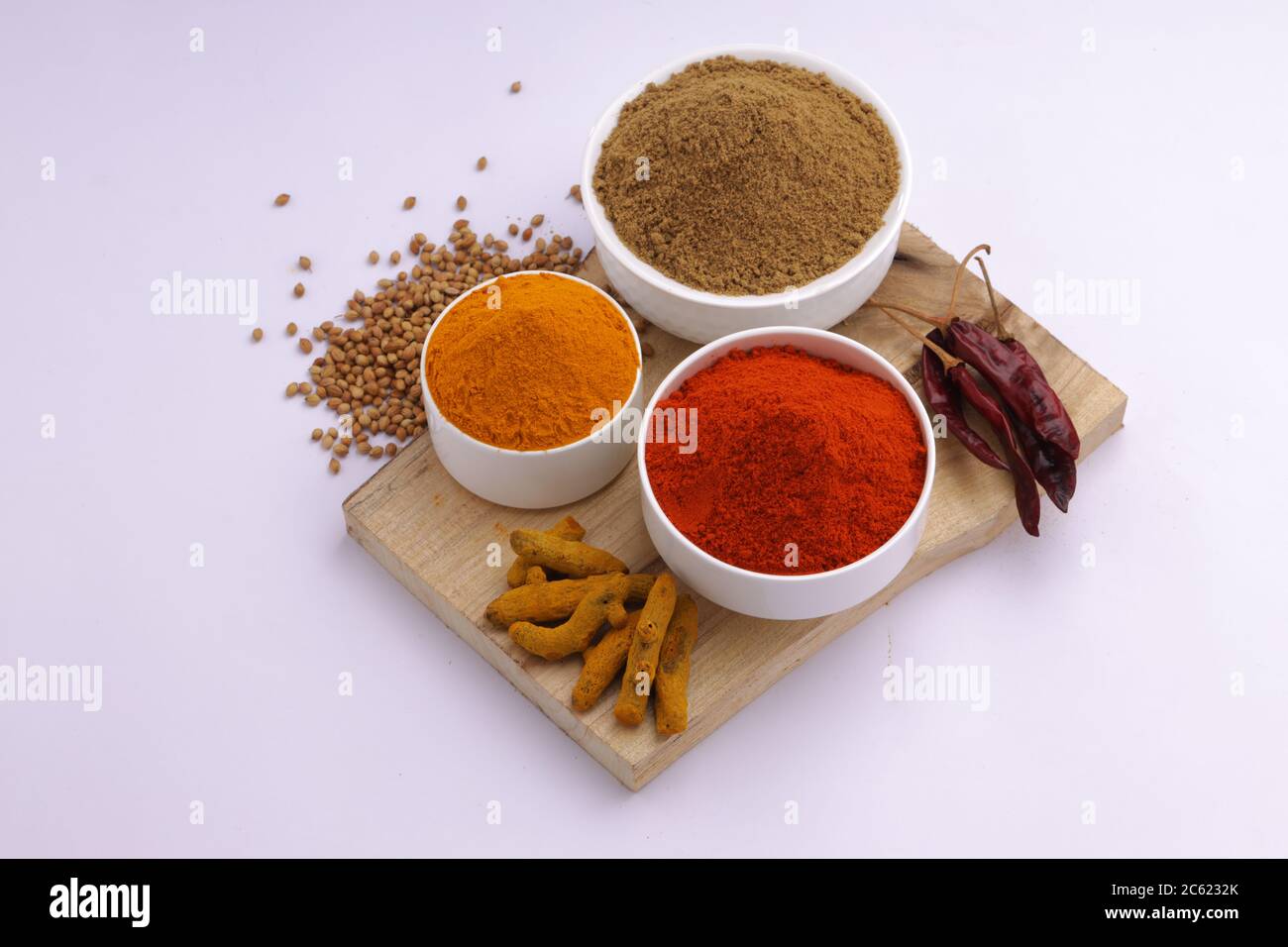 Spezie indiane Chili, curcuma e coriandolo sono le tre spezie di base utilizzate per il curry indiano o piatti, disposti in ciotole bianche Foto Stock