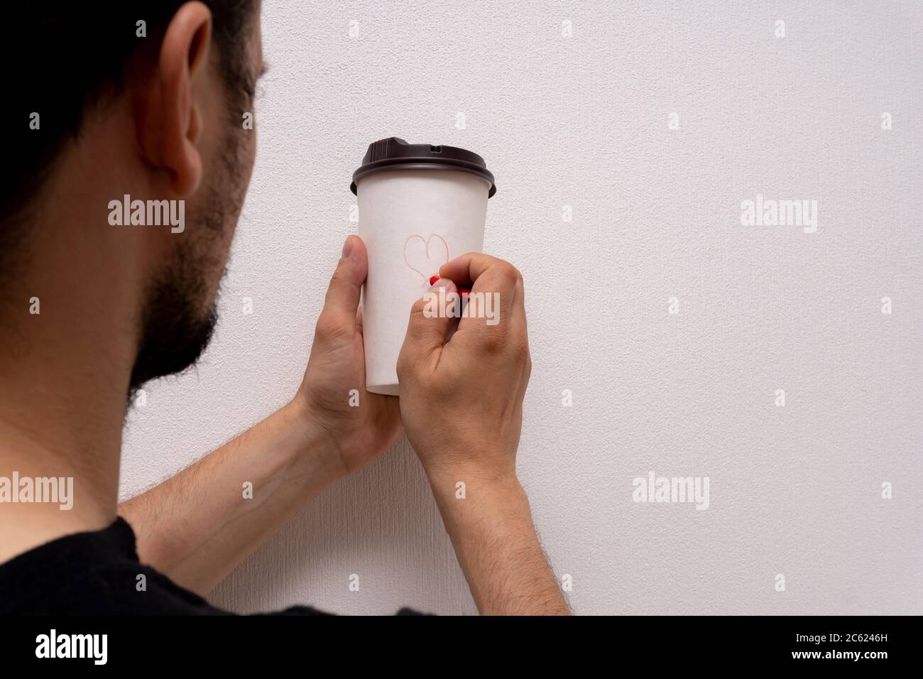 L'uomo caucasico tiene la tazza di caffè di carta e dipinge l'immagine del cuore bella per l'amante Foto Stock