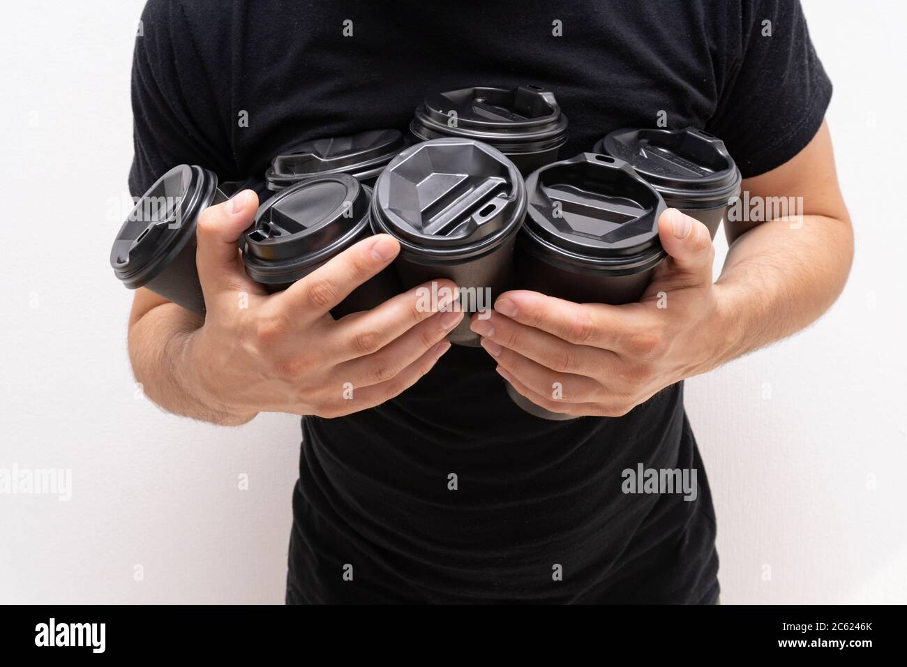 Caucasica mans mani con caffè togo in tazze di carta con coperchi neri, senza viso Foto Stock