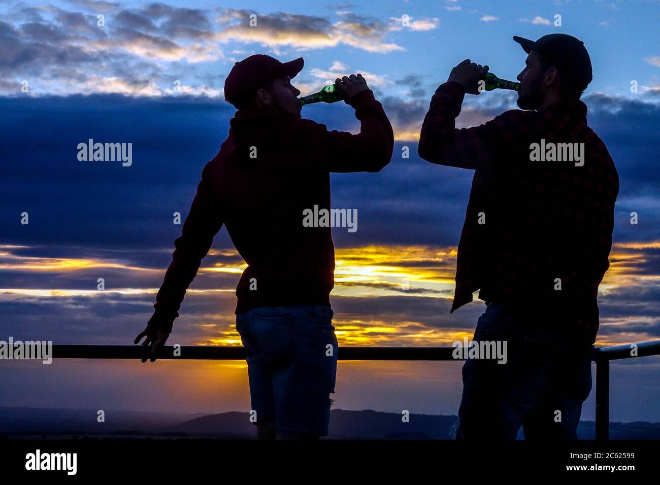 Silhouette di due uomini che bevono birra, gli amici bevono Foto Stock