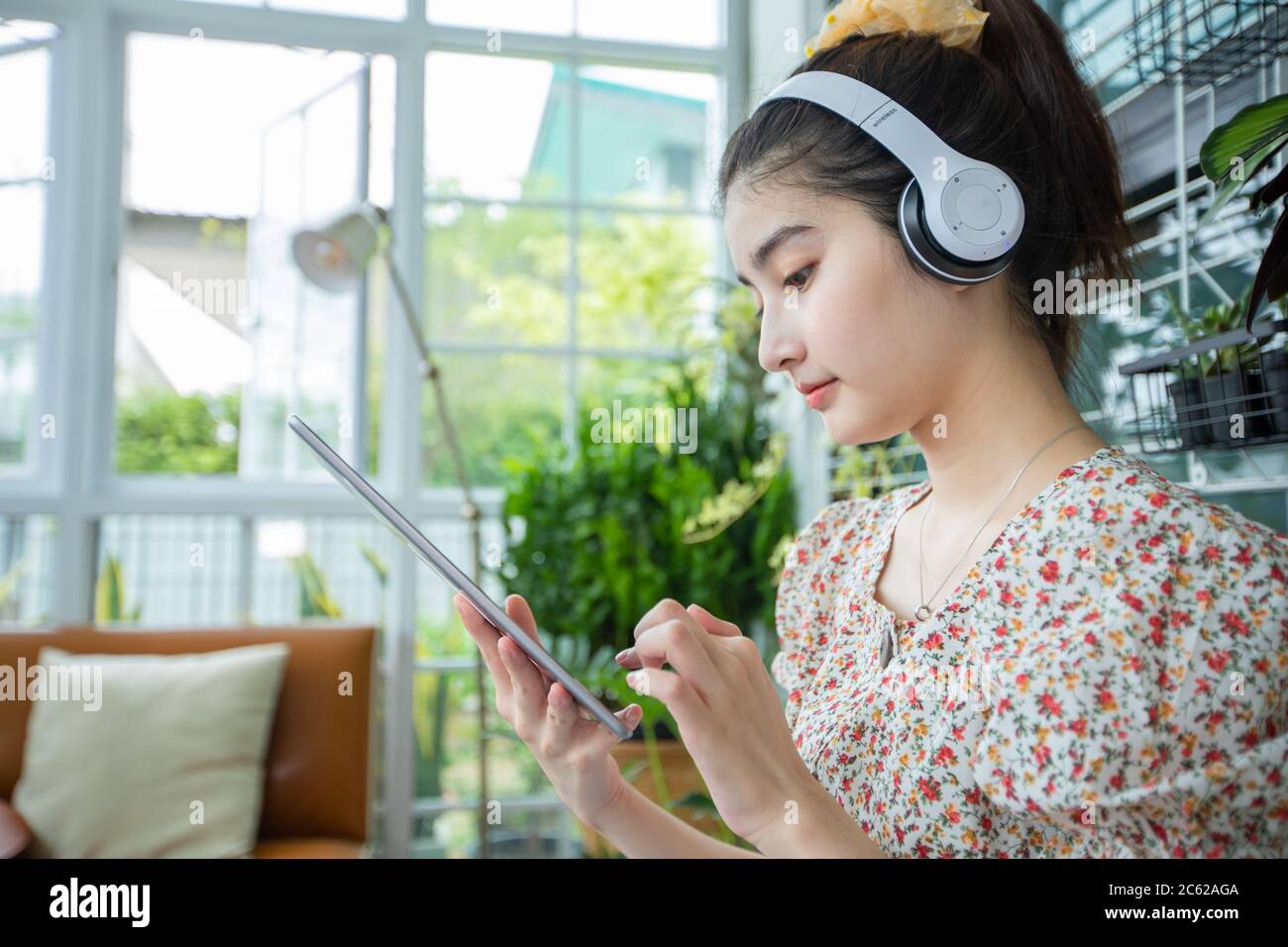 Donne asiatiche che indossano cuffie e utilizzano un telefono cellulare e un tablet digitale per ascoltare musica e cantare in una giornata rilassante a casa Foto Stock