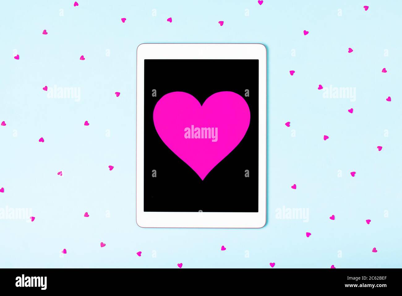 Tablet su sfondo blu con cuori carini. Il concetto di formazione online, sito web di incontro, amore in internet, amore per il tuo gadget e la tecnologia, corrispondenza amore, sorpresa. Disposizione piatta Foto Stock