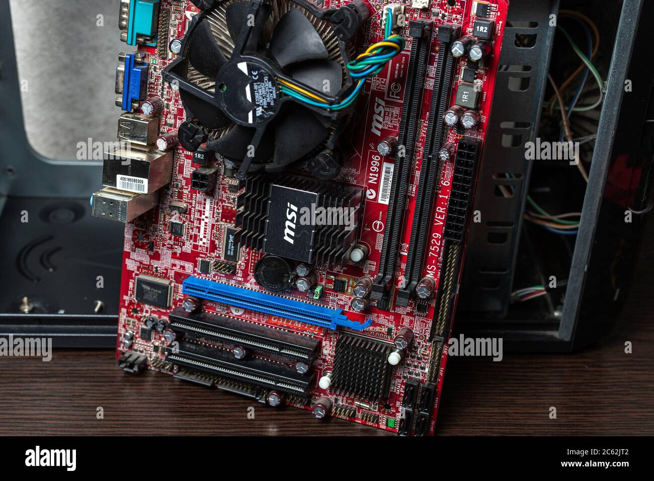 Ucraina - 25 aprile 2020: Scheda madre del computer scollegata vicino al case su una superficie marrone. Vista ravvicinata, concetto di idea di fondo Foto Stock