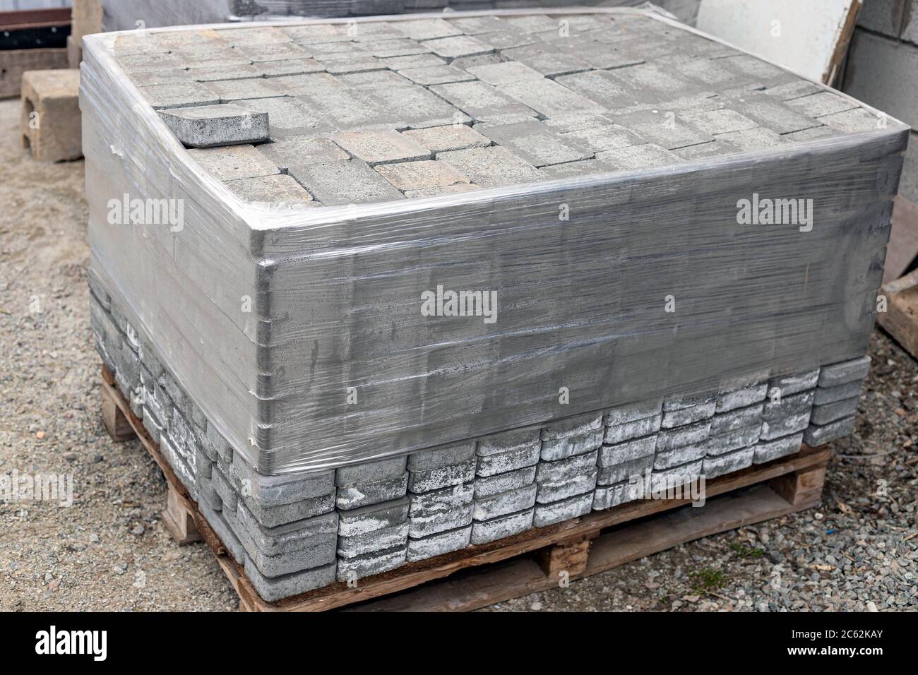 Pila di nuovi pietre grigie per pavimentazione su pallet in legno fissato con avvolgimento elastico. Materiale da costruzione per la ricostruzione del pavimento Foto Stock