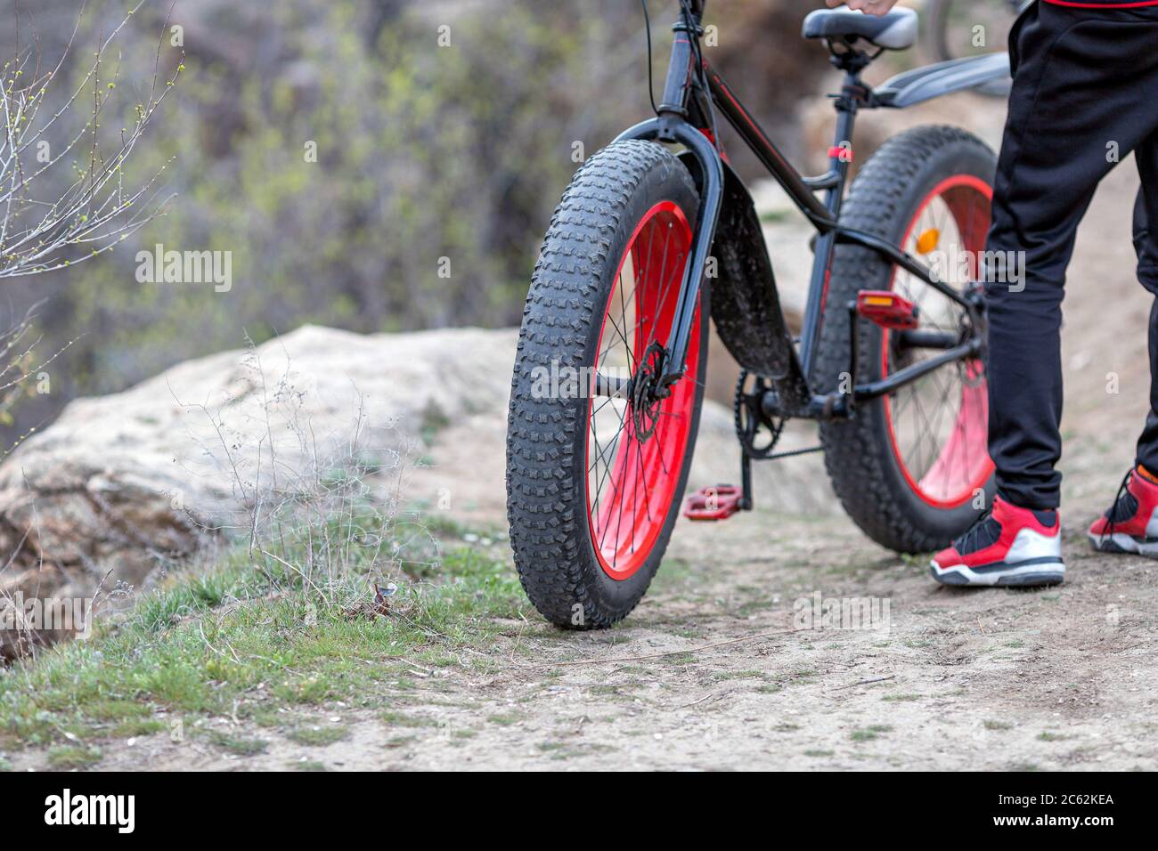 Primo piano dell'uomo che indossa abiti rossi e neri e si trova vicino alla bicicletta. Idea di sport Foto Stock