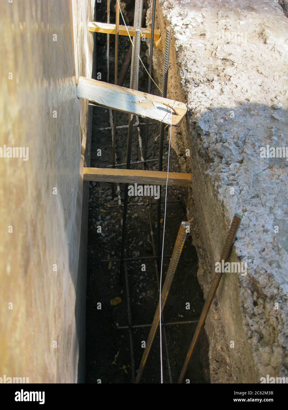 Trincea di fondazione con rinforzo per la costruzione della recinzione. Foto Stock