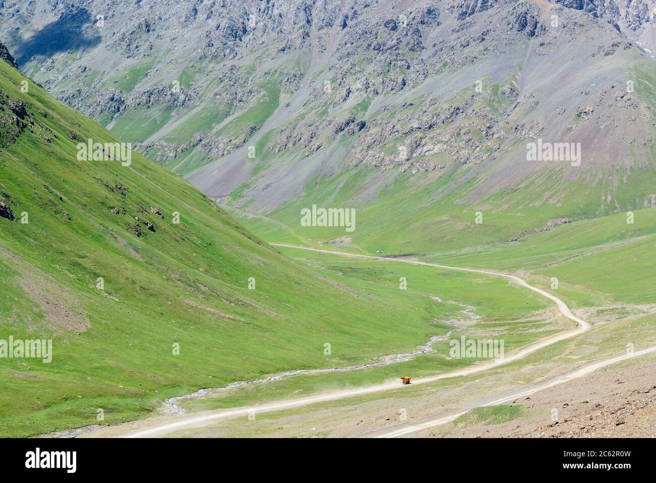 Camion arancione che guida in una valle nelle montagne Tian Shan del Kirghizistan Foto Stock