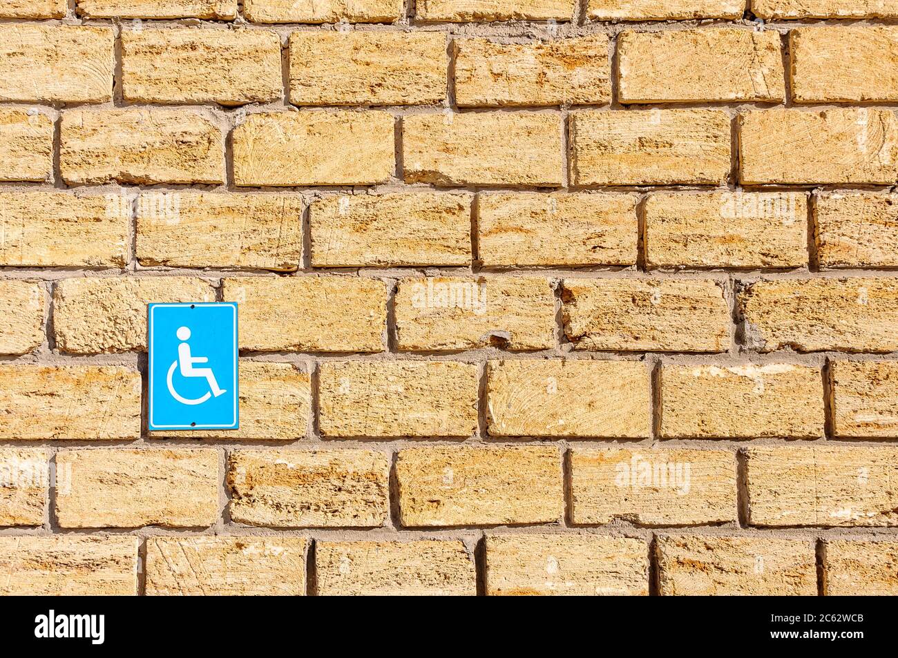 Cartello per disabili su un muro di pietra. Foto Stock