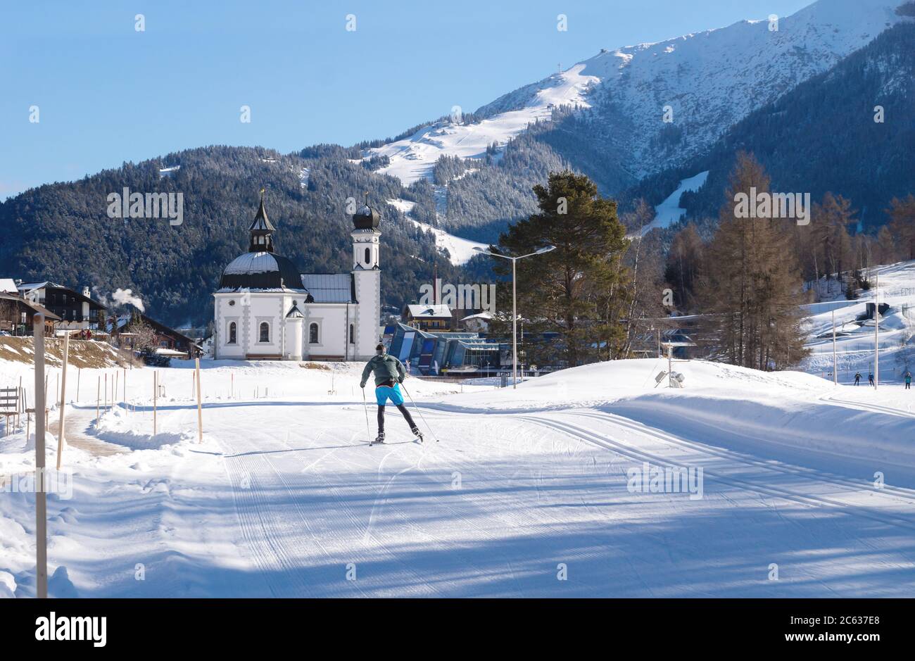 Sci di fondo su pista soleggiata verso la tipica chiesa pittoresca austriaca, Seefeld, Austria Foto Stock