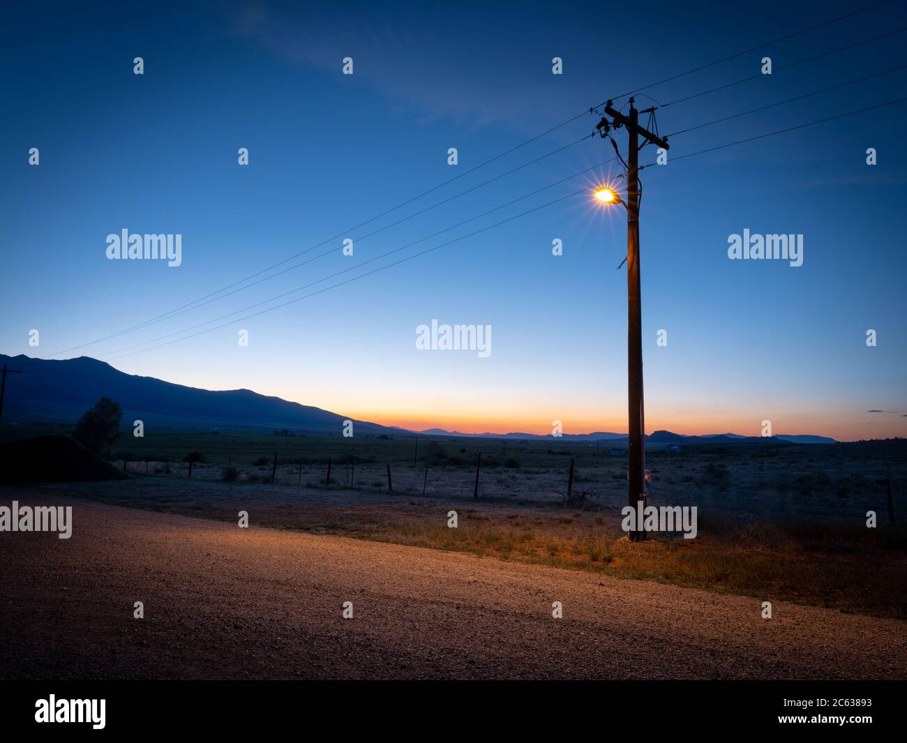 Lampione luminoso solo su strada sterrata rurale, Colorado, USA Foto Stock