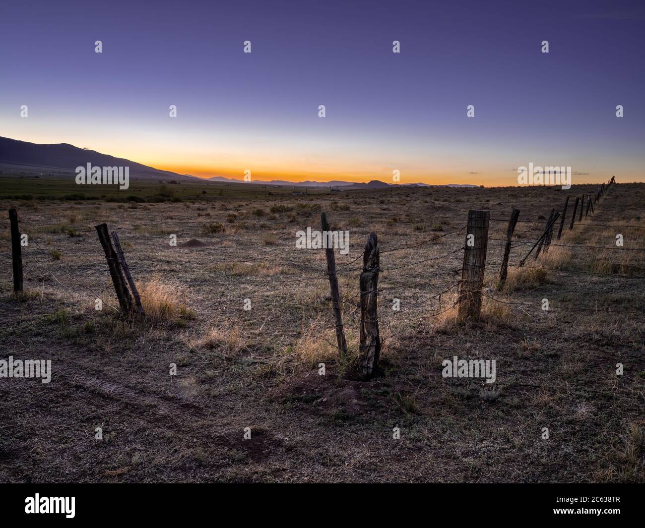 Vecchio recinto di filo spinato al tramonto con le montagne, Westcliffe, Colorado USAS Foto Stock