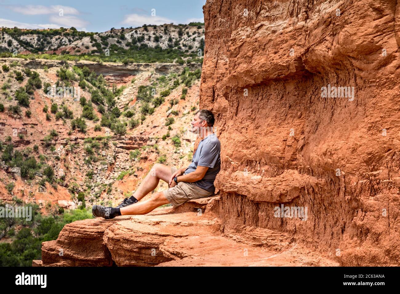 Uomo seduto sul bordo del Lighthouse Rock, Palo duro Canyin state Park, Texas Foto Stock