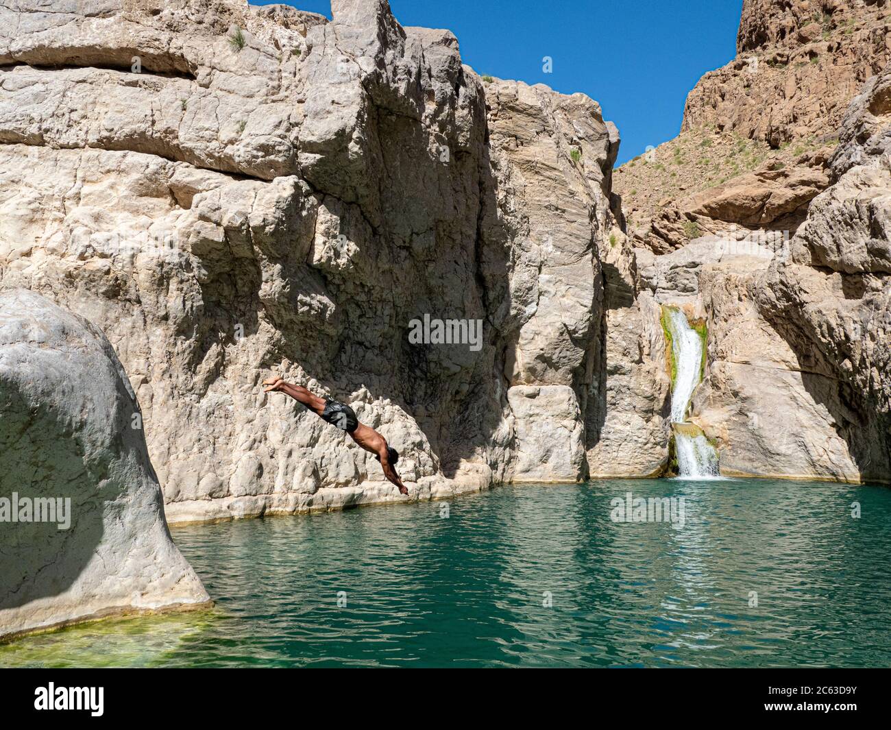Giovane uomo che si tuffa in piscine naturali a Wadi Bani Khalid, Sultanato di Oman. Foto Stock