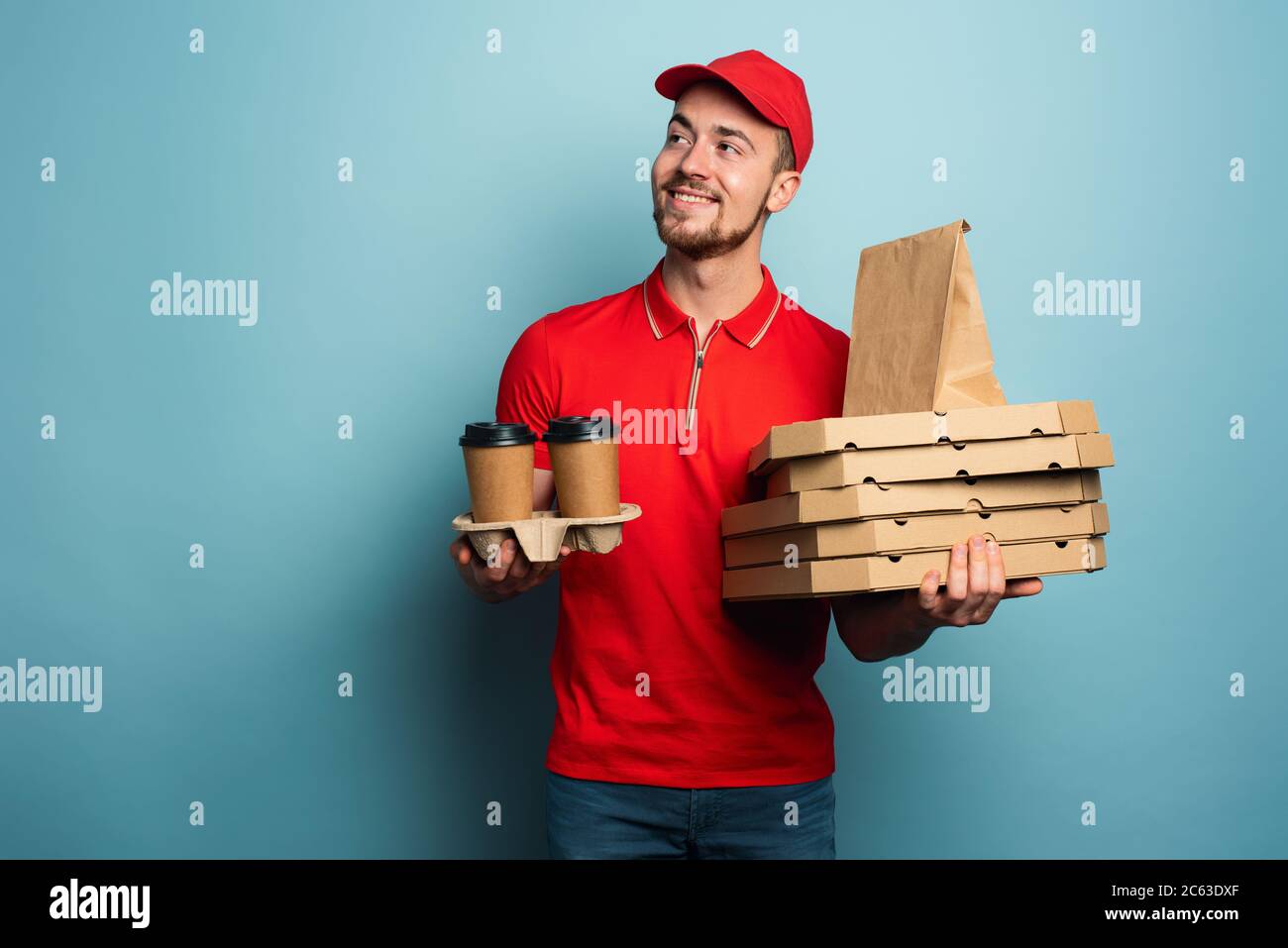 Il corriere è felice di consegnare caffè caldo, pizza e cibo. Sfondo ciano Foto Stock