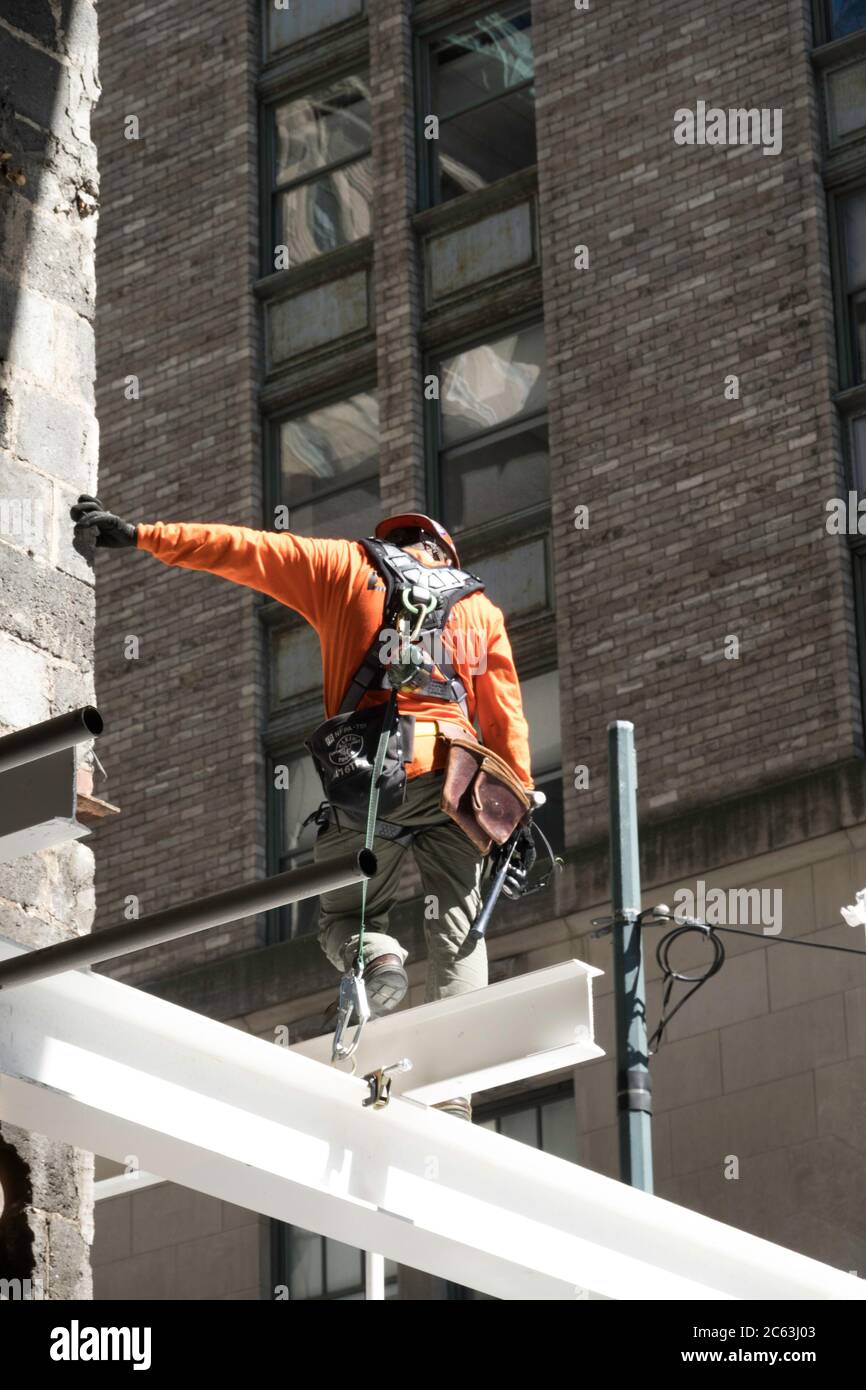 Lavoratore di costruzione in piedi su e i-beam in un cantiere di grattacieli a New York City, Stati Uniti Foto Stock
