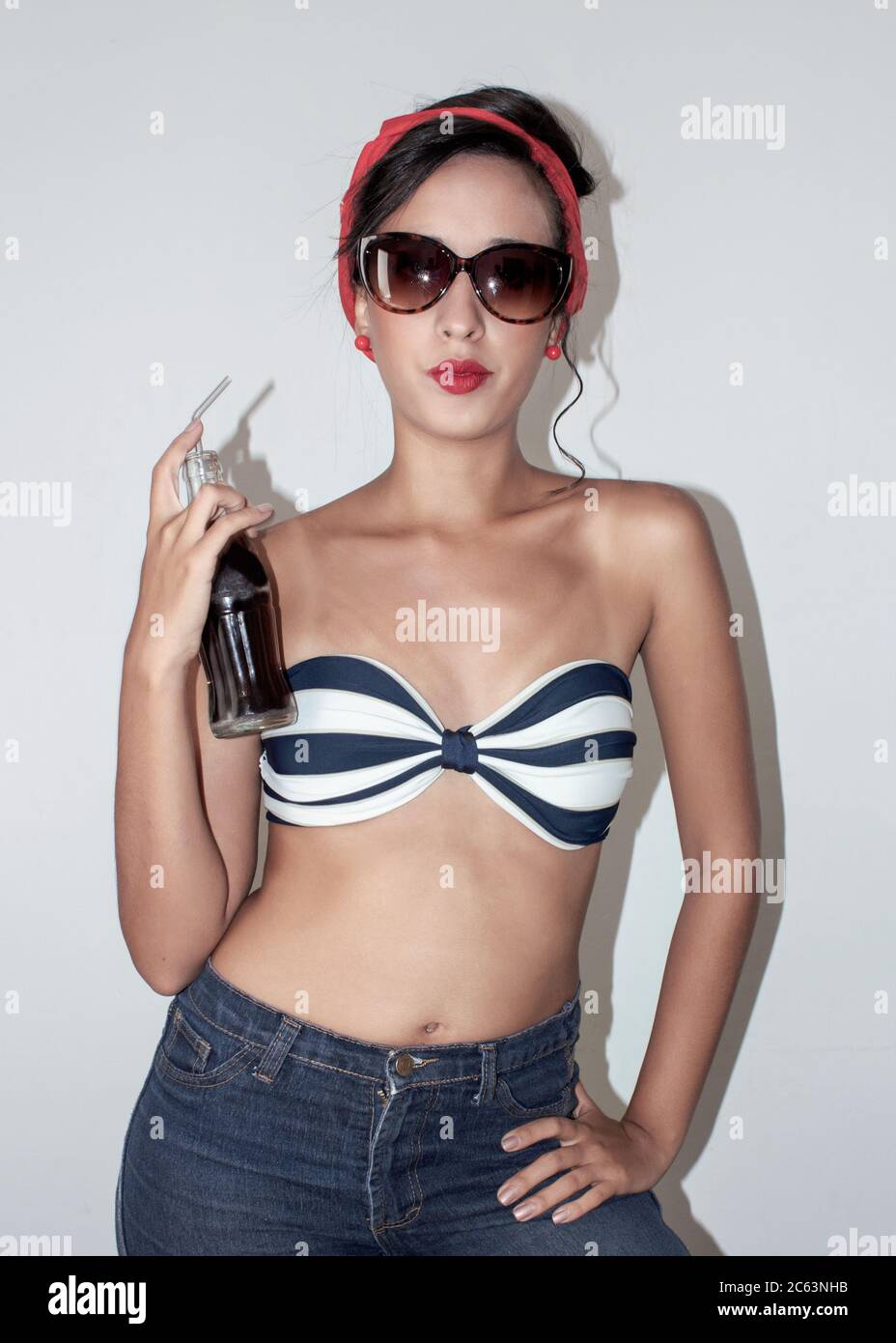 donna modellante con costume da bagno e sciarpa rossa e una bottiglia in mano Foto Stock