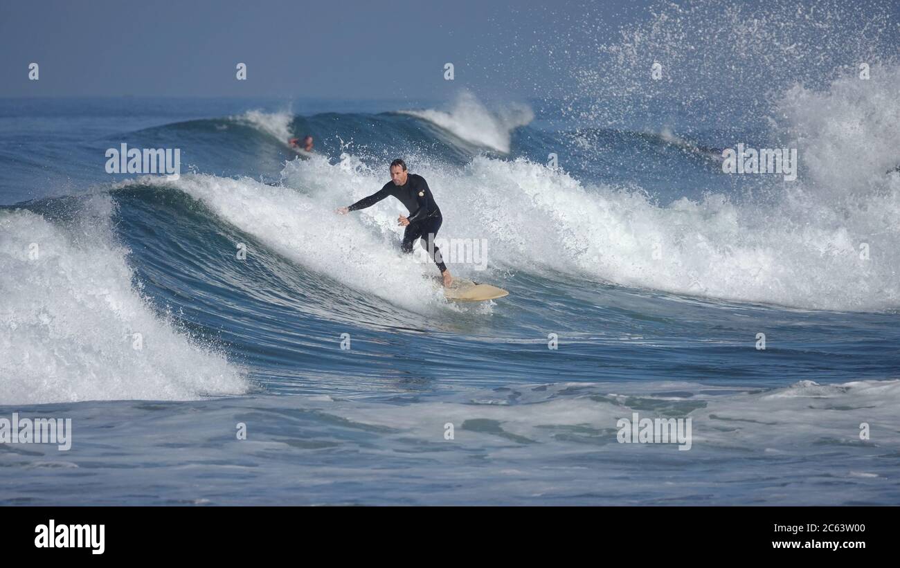 Surfista maschile a cavallo di una grande onda in una giornata con grande surf. Foto Stock