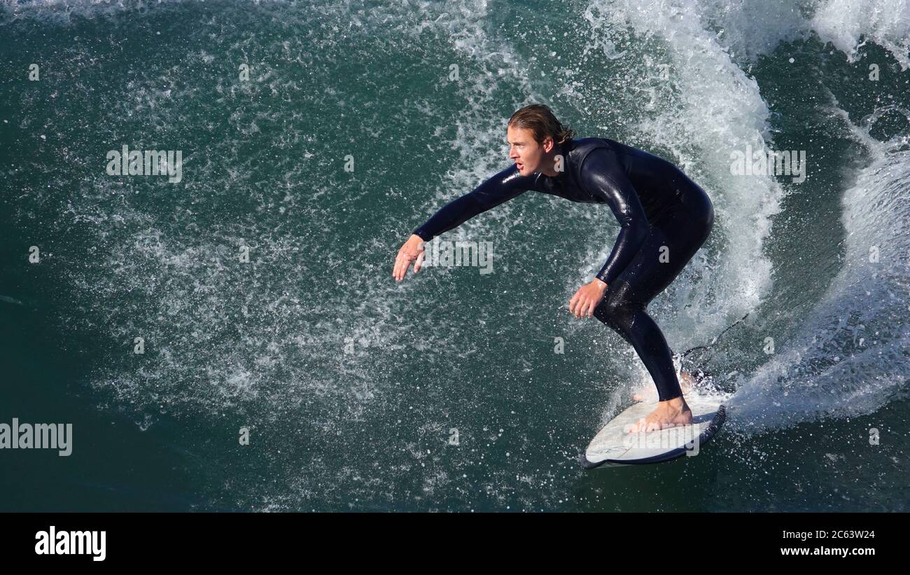 Giovane surfista maschile che cavalca una grande onda Foto Stock