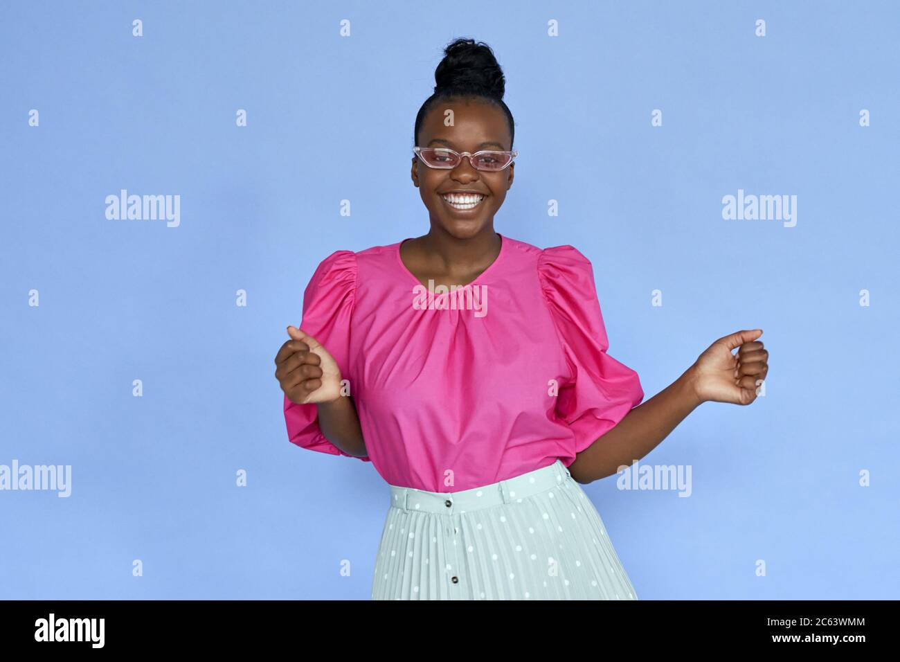 Donna africana felice che indossa un panno alla moda e occhiali da sole rosa isolati sul lilla. Foto Stock