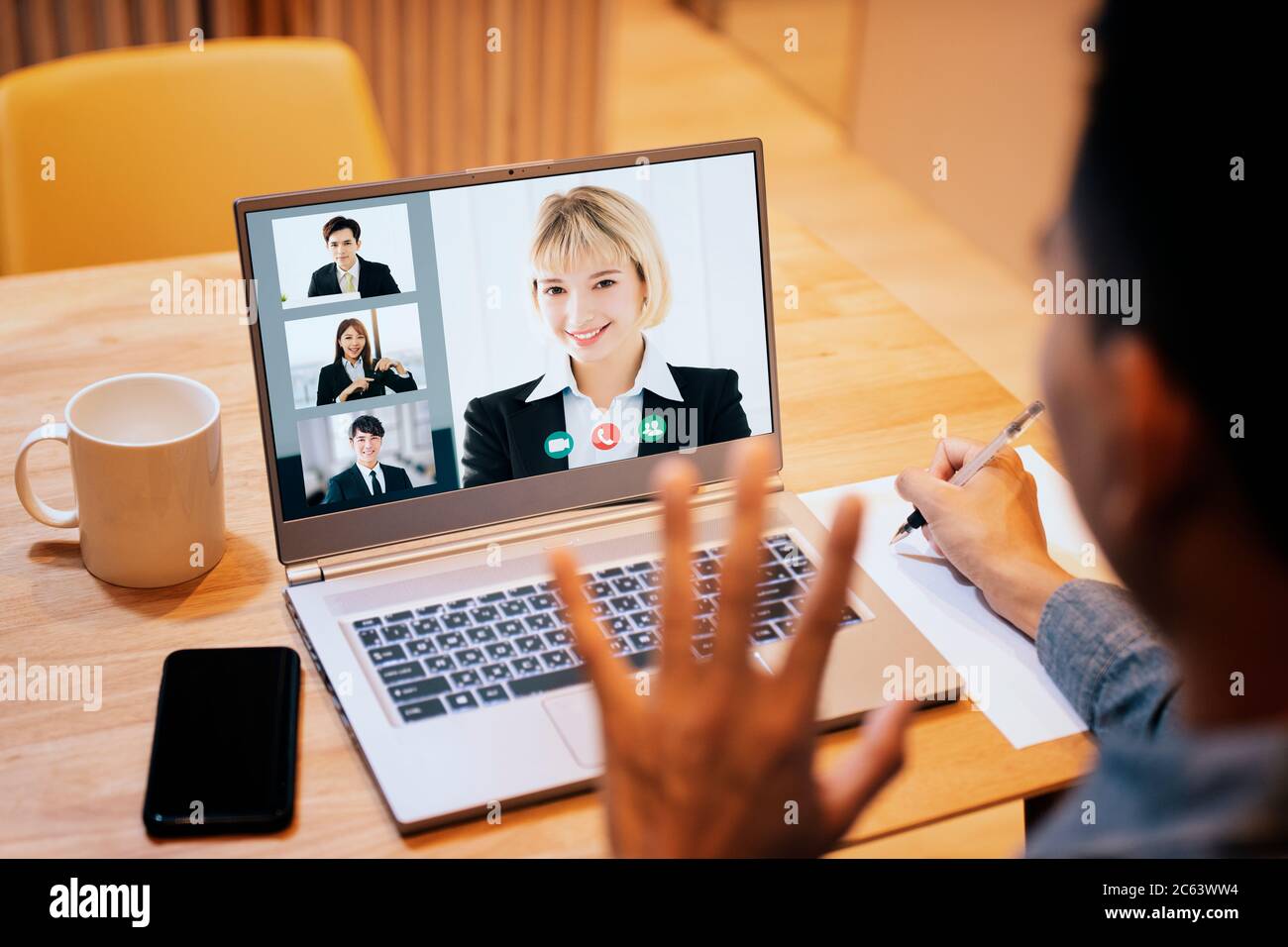giovane uomo che lavora a casa e utilizza un computer portatile con videoconferenza Foto Stock