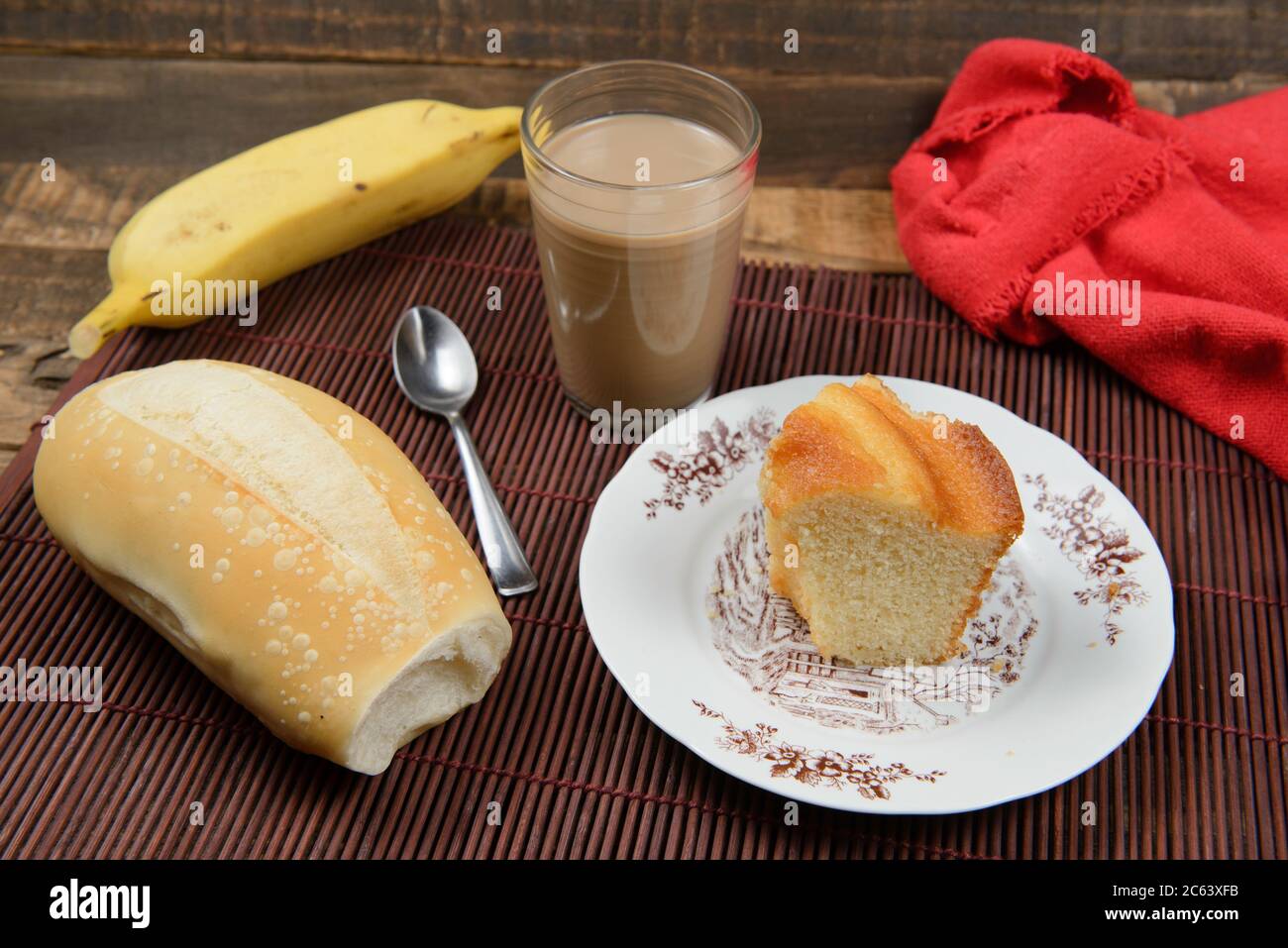 tipica colazione brasiliana, con tazza di caffè con latte, pane, torta e banana frutta Foto Stock