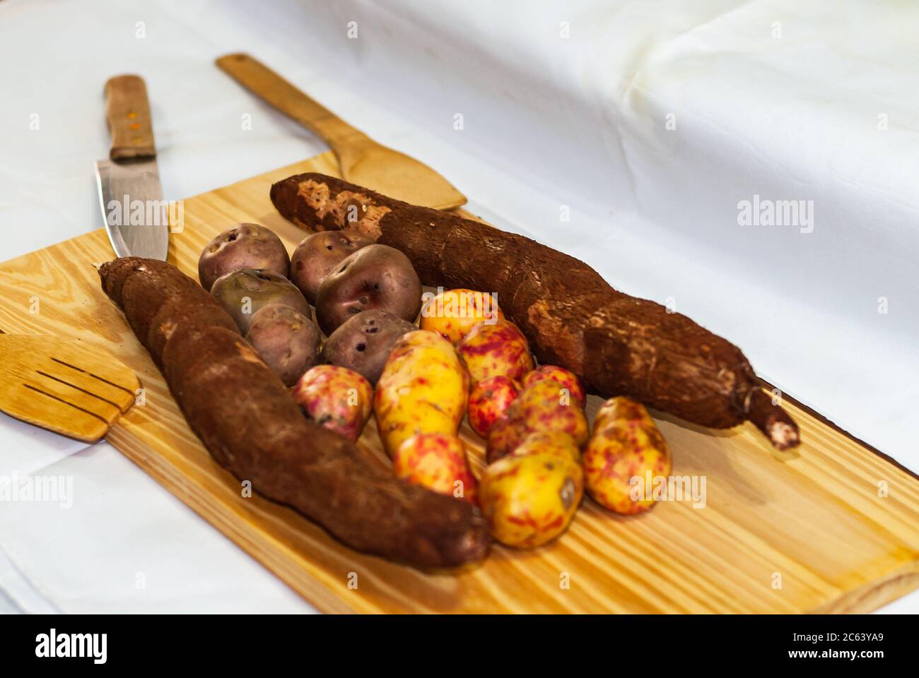 Yucca cruda sulla tavola di legno, esculenta Manihot. (Tubero crudo di manioca) con patate regionali delle Ande in un mercato in Perù, Bolivia, Argentina, s. Foto Stock