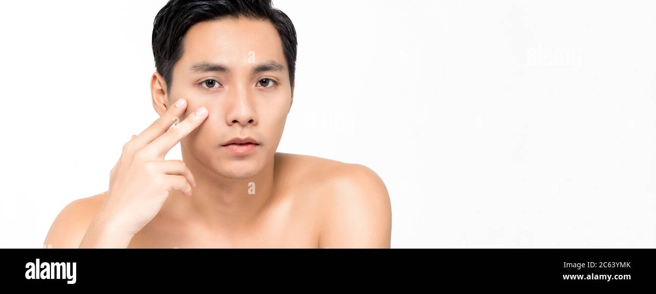 Bel giovane uomo asiatico che tocca sotto la pelle degli occhi isolato su sfondo bianco banner per concetti di bellezza Foto Stock
