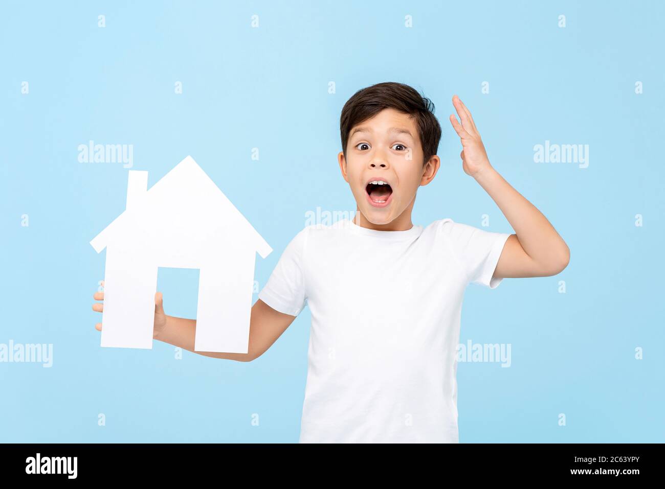 Carino bambino che tiene il modello di ritaglio casa che è scioccato e che spazia su sfondo azzurro isolato Foto Stock