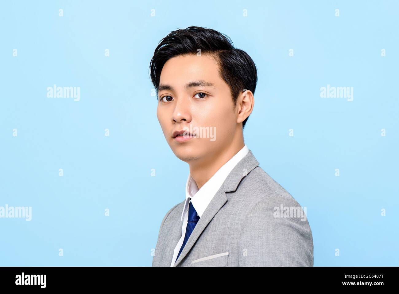 Ritratto di giovane bell'uomo asiatico in tuta formale isolato su sfondo azzurro Foto Stock