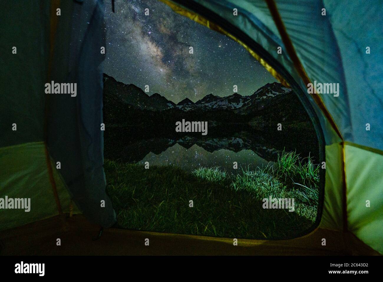 La Via Lattea e il suo riflesso possono essere visti attraverso una porta tenda che si erge sulle montagne Foto Stock