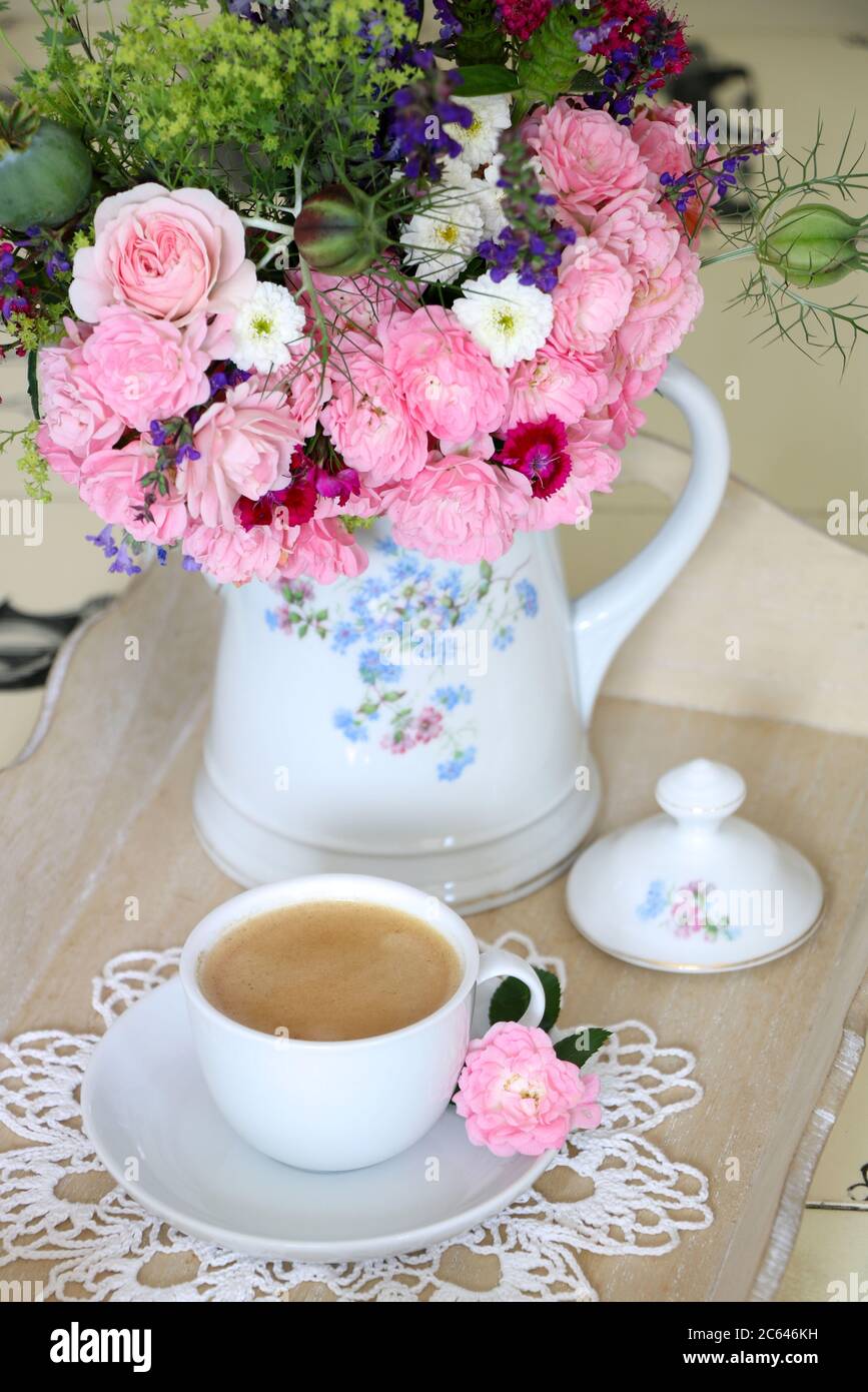 bouquet di rose rosa e fiori estivi in lattina di caffè vintage e tazza di caffè come decorazione della tabella Foto Stock
