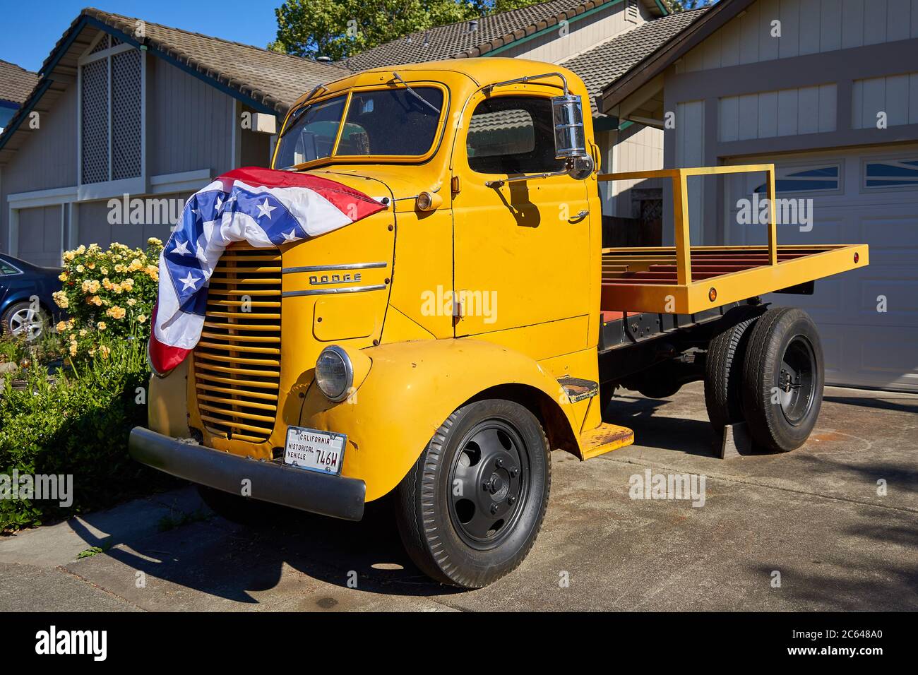 Camion Classic Dodge con esterno giallo e bandiera americana sul cofano. Veicolo storico della California a Windsor, California. Foto Stock