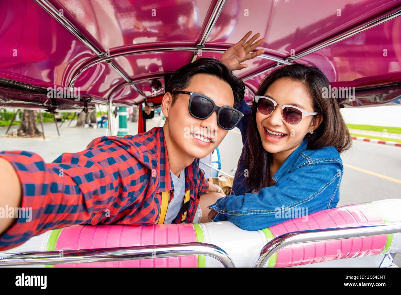 Allegri giovani turisti asiatici coppie che prendono selfie mentre viaggiano su locale colorato Tuk Tuk Tuk taxi esplorare la città di Bangkok, Thailandia Foto Stock